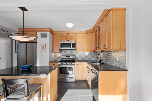 a kitchen with stainless steel appliances granite countertop a sink a stove and a refrigerator