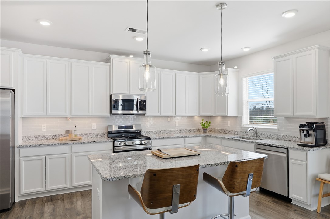 804 Spring Orchard Drive Lyman, SC 29365 - Photo 13 of 47 Bright and functional kitchen featuring sleek appliances, generous counter space, a custom tile backsplash not included in the builder’s standard package, and upgraded under-cabinet and above-cabinet lighting.