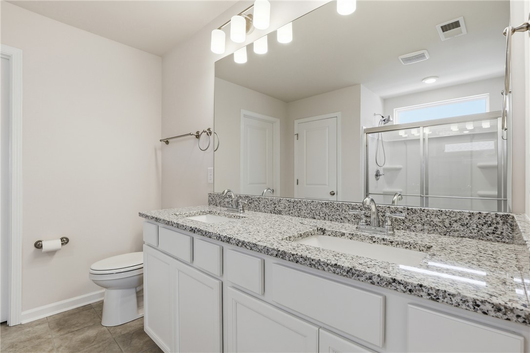 804 Spring Orchard Drive Lyman, SC 29365 - Photo 27 of 47 This primary bathroom features a double vanity, a glass-enclosed shower, one of two large walk in closet offering both comfort and functionality.