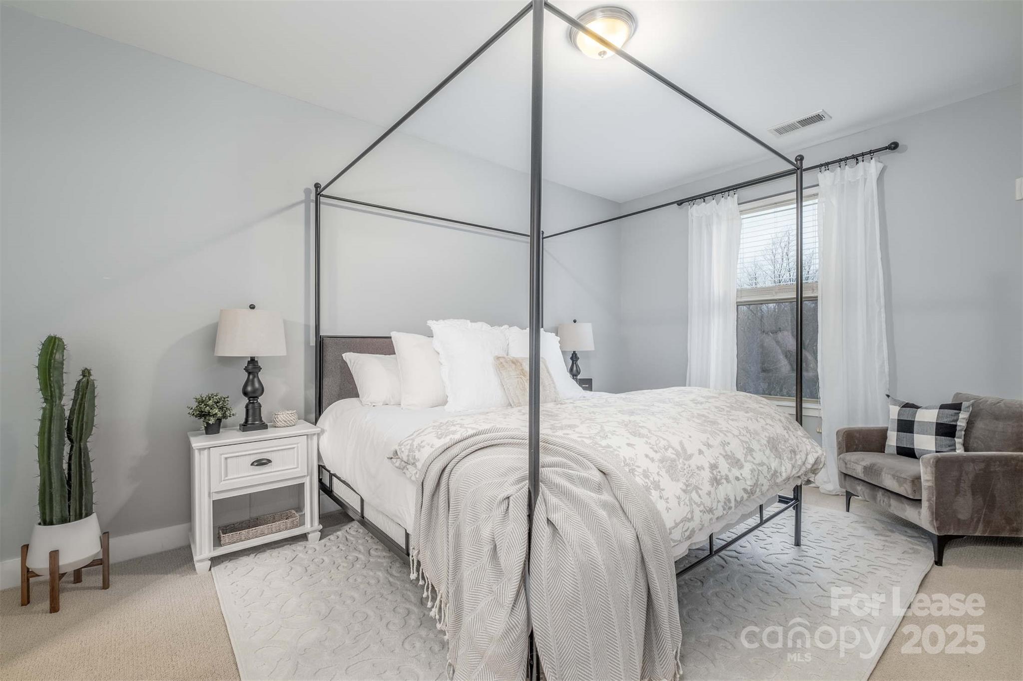 630 Calvert Street, Unit 409 Charlotte, NC 28208 - Photo 7 of 8 a bedroom with a bed and a flat tv screen on the dresser