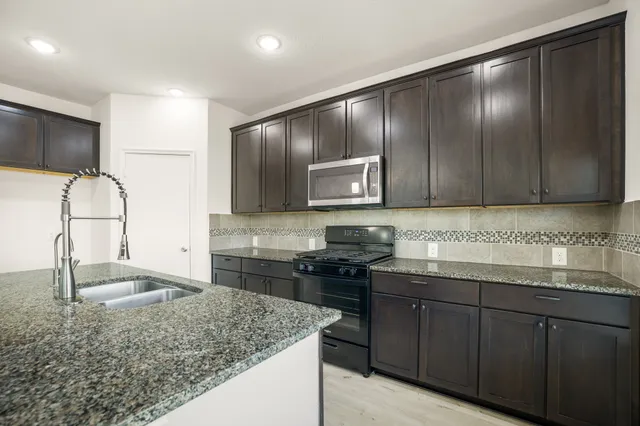 a kitchen with stainless steel appliances granite countertop wooden cabinets and a sink