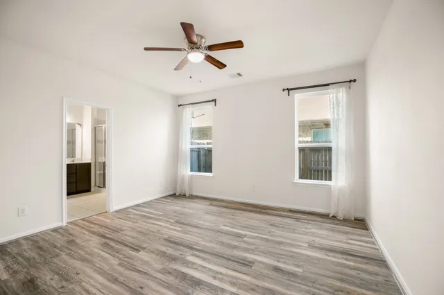 a view of empty room with wooden floor and fan