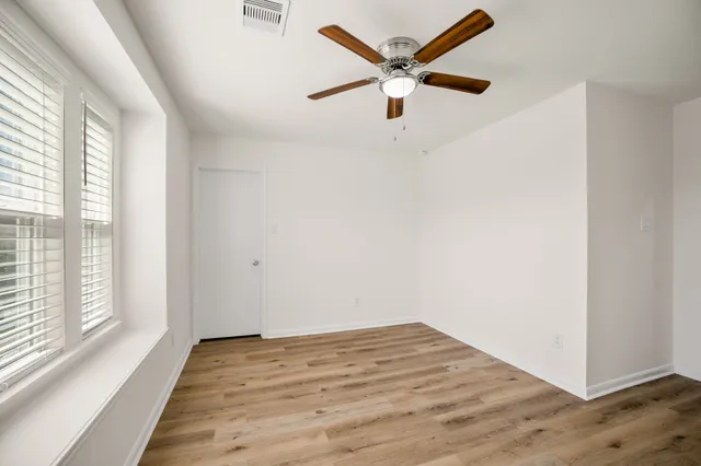 an empty room with wooden floor and windows