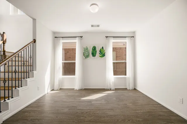 a view of an empty room with wooden floor and stairs