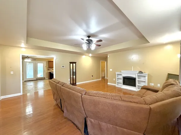 a view of a livingroom with a fireplace a ceiling fan and wooden floor