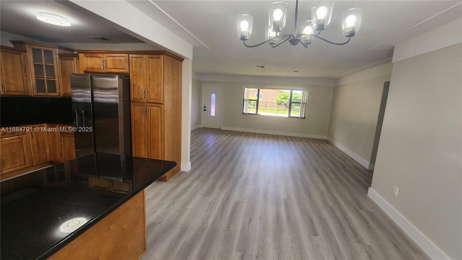 3295 Northwest 214th Street, Unit 3295 Miami Gardens, FL 33056 - Photo 6 of 19 an empty room with wooden floor and windows