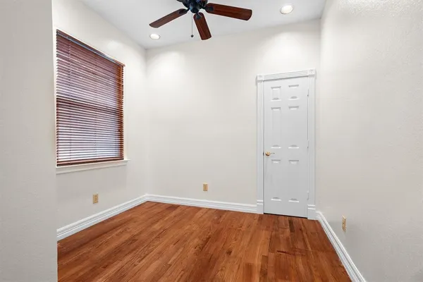 an empty room with a hardwood and ceiling fan