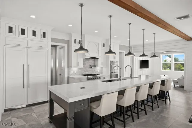 a kitchen with stainless steel appliances kitchen island a table chairs sink and cabinets