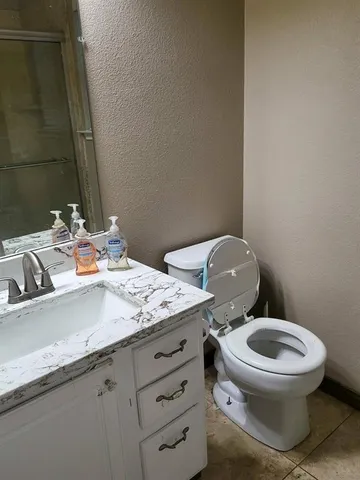a bathroom with a granite countertop toilet sink and mirror