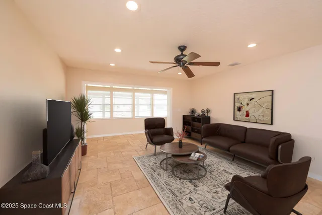 a living room with furniture ceiling fan and a flat screen tv