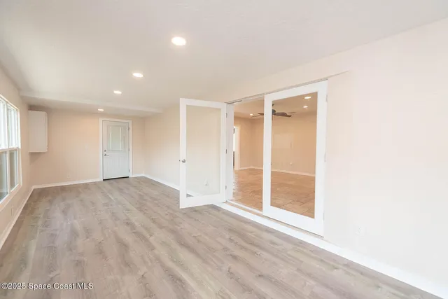 an empty room with wooden floor and windows