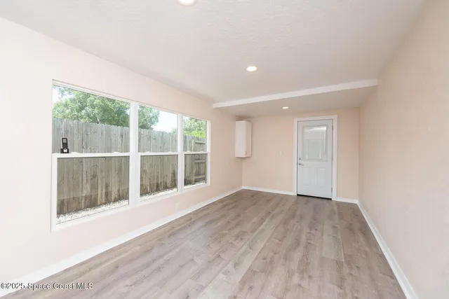 an empty room with wooden floor and windows