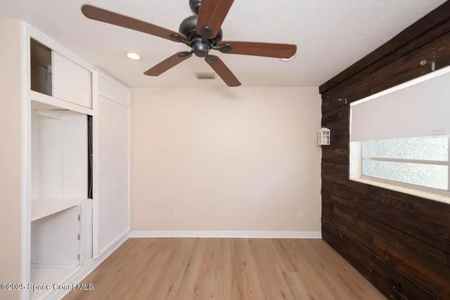 a view of empty room with wooden floor and fan