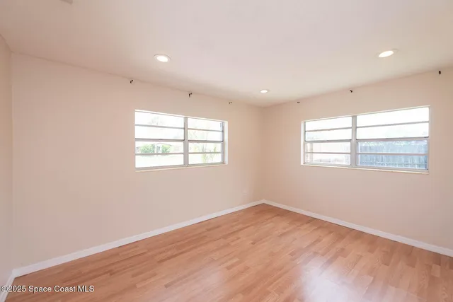 an empty room with wooden floor and windows