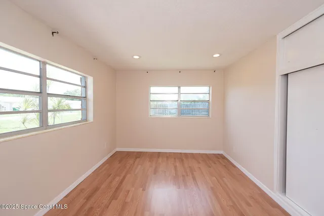 an empty room with wooden floor and windows