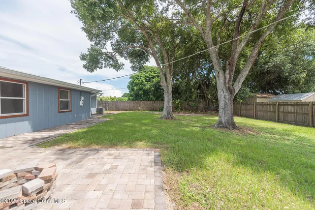 a view of a backyard with large trees and wooden fence