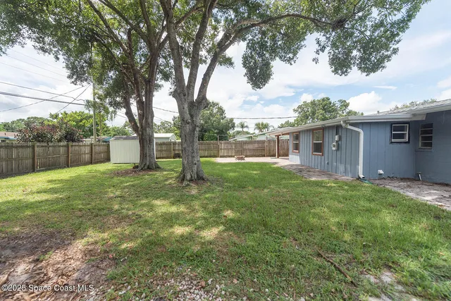 a view of a house with backyard and a tree