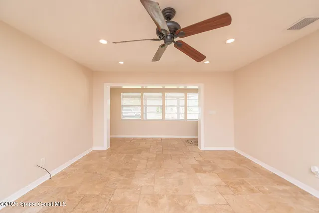 an empty room with windows and fan