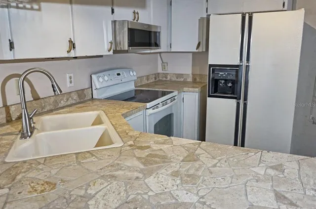 a kitchen with stainless steel appliances granite countertop a sink a stove top oven a refrigerator with granite countertops and cabinets