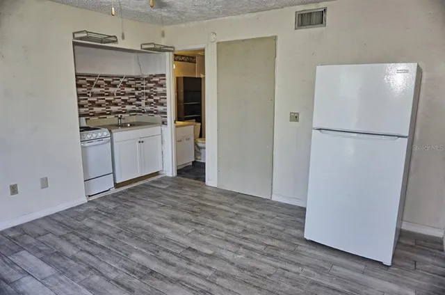 a view of a kitchen with wooden floor and a refrigerator