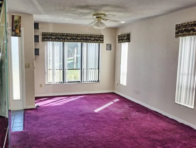 an empty room with windows and chandelier fan
