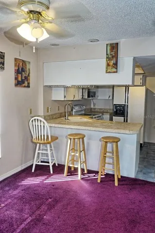 a view of kitchen with stainless steel appliances granite countertop dining table chairs and a chandelier