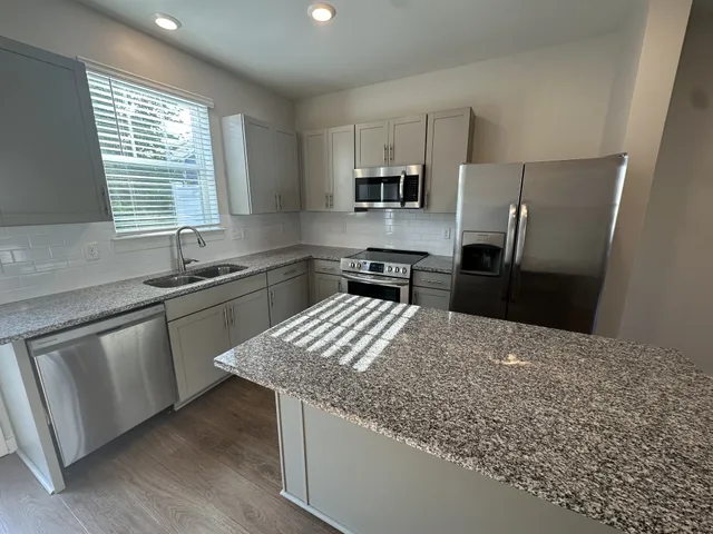 a kitchen with stainless steel appliances kitchen island granite countertop a sink stove and refrigerator