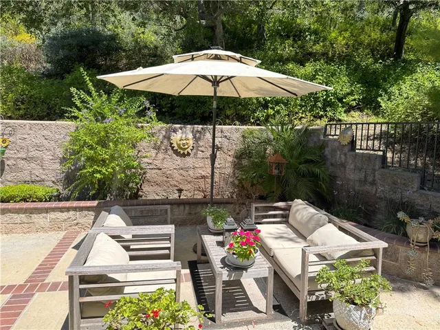 a view of a chairs and table under an umbrella in backyard