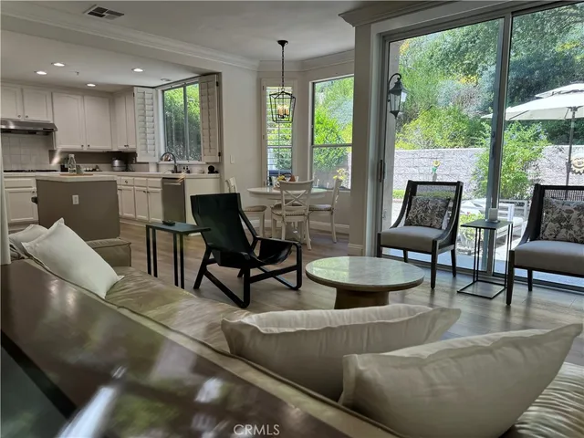 a living room with couches and kitchen view with a large window