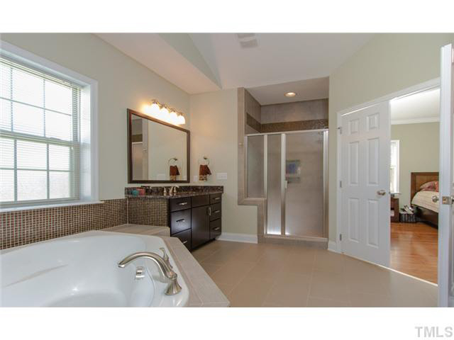 200 Swift Creek Crossing Durham, NC 27713 - Photo 14 of 25 a bathroom with a sink a large mirror and a bathtub