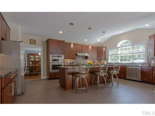 200 Swift Creek Crossing Durham, NC 27713 - Photo 9 of 25 a kitchen with stainless steel appliances kitchen island granite countertop a refrigerator a stove a sink a dining table and chairs
