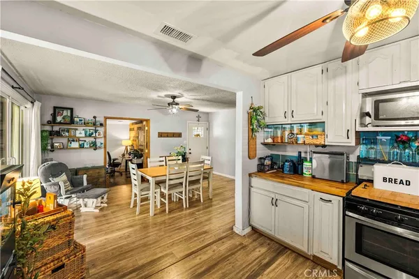 a kitchen with stainless steel appliances kitchen island granite countertop a stove top oven a sink a dining table and chairs with wooden floor