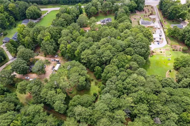 an aerial view of residential house with outdoor space and trees all around