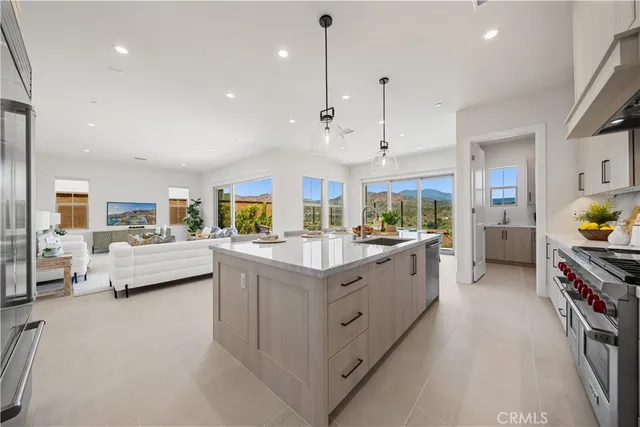 a large white kitchen with kitchen island a large counter space a sink stainless steel appliances and cabinets
