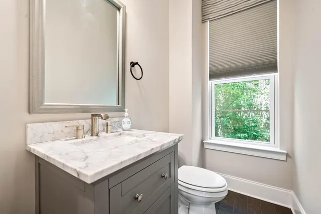 a bathroom with a granite countertop sink toilet and mirror