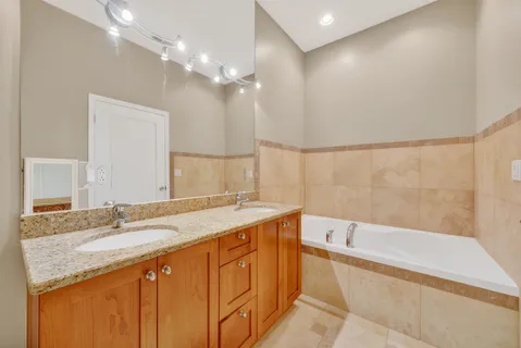 a bathroom with a granite countertop sink a large mirror and a bathtub