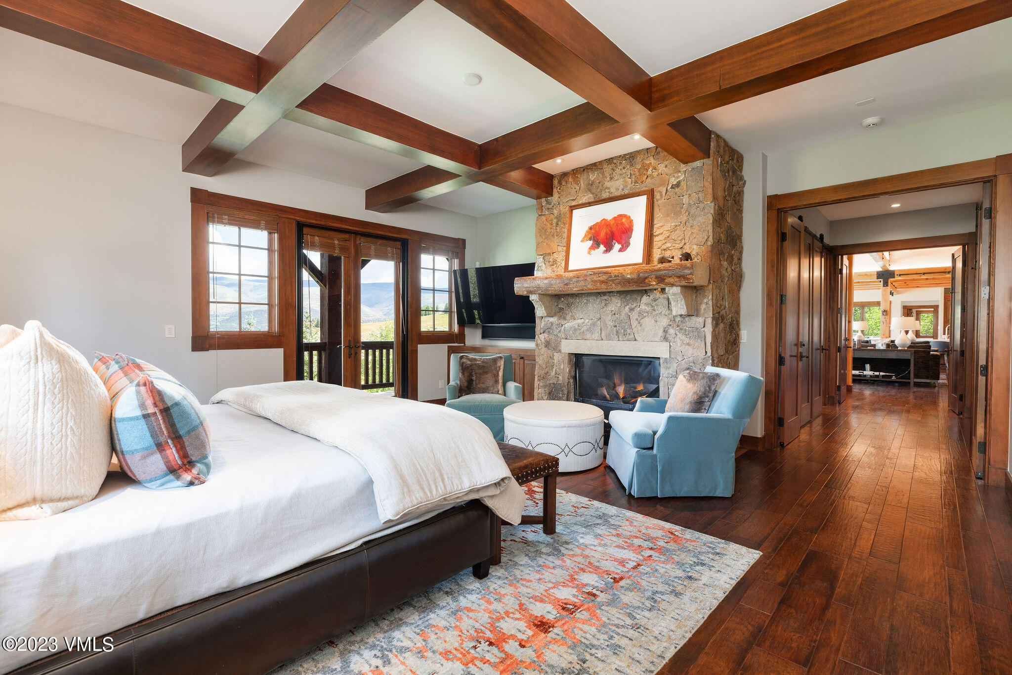520 Old Creamery Road Edwards, CO 81632 - Photo 23 of 78 a bedroom with a large bed a flat tv screen and a fireplace with wooden floor