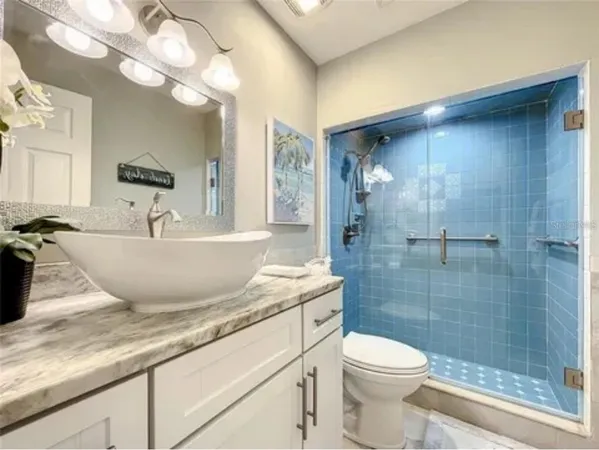 a bathroom with a granite countertop sink a toilet and shower