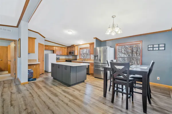 a kitchen with stainless steel appliances wooden floors dining table and chair
