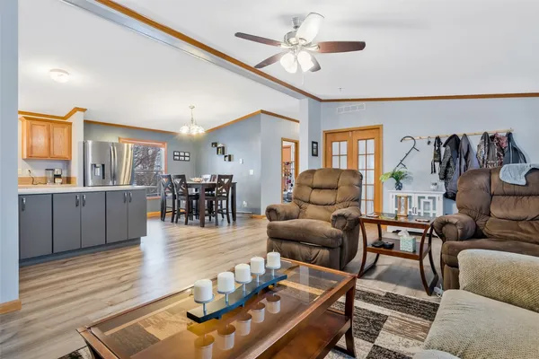 a living room with furniture kitchen view and a wooden floor