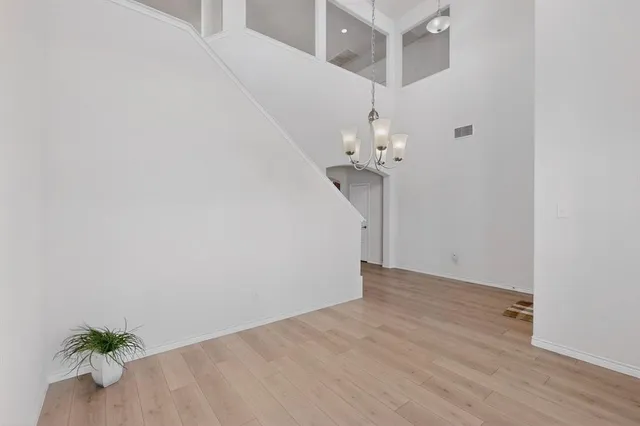 a view of a hallway with wooden floor and chandelier