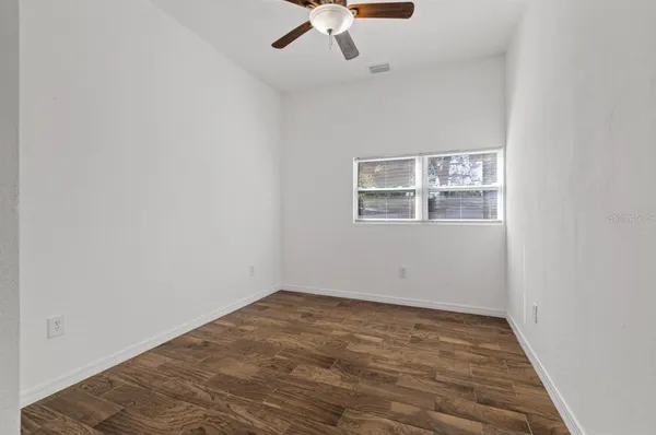 an empty room with a ceiling fan and wooden floor