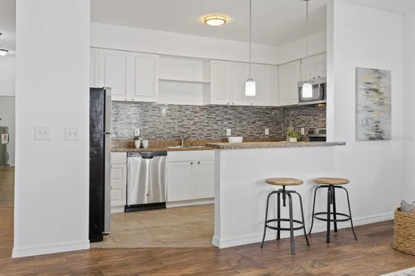 a kitchen with stainless steel appliances granite countertop a table chairs sink and cabinets