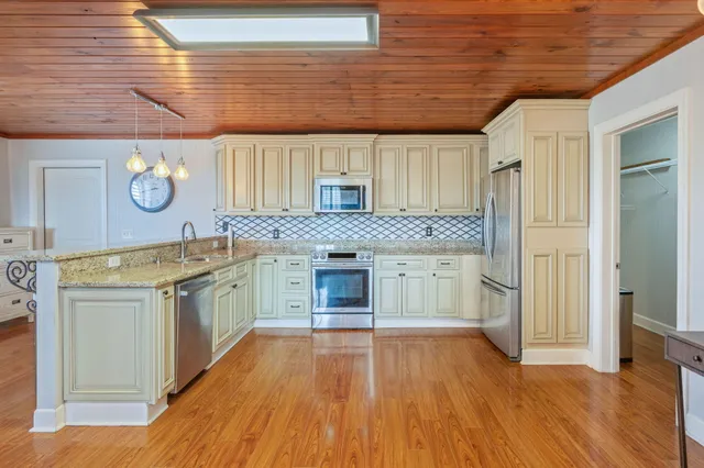 a kitchen with stainless steel appliances granite countertop a stove a sink and a microwave oven with white cabinets