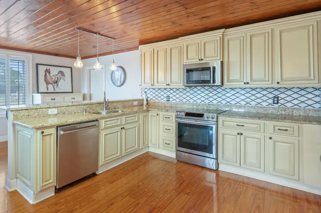 a kitchen with stainless steel appliances granite countertop a chairs a sink and a refrigerator