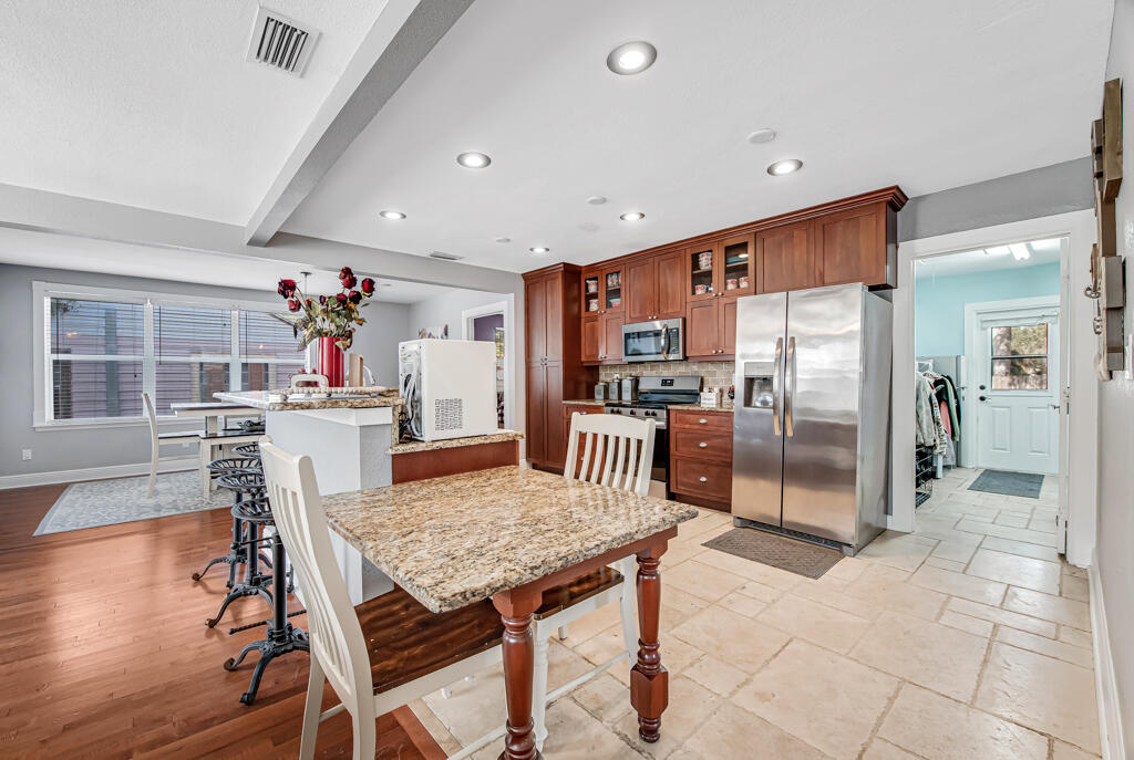 416 Deane Duff Street Clewiston, FL 33440 - Photo 4 of 45 a kitchen with stainless steel appliances kitchen island granite countertop a refrigerator a stove a kitchen island and chairs with wooden floor