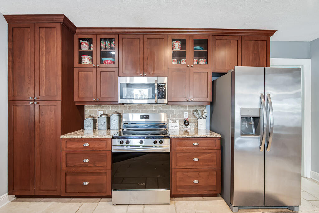 416 Deane Duff Street Clewiston, FL 33440 - Photo 9 of 45 a kitchen with stainless steel appliances granite countertop a refrigerator and a stove top oven
