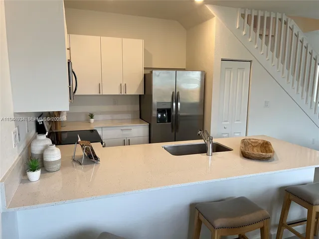 a kitchen with a sink a counter and chairs