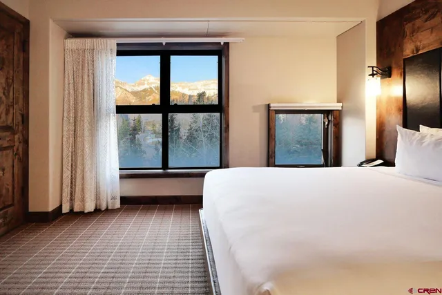 a large white bed in a room next to a window