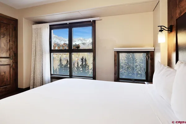 a bedroom with a large window and a wooden floor